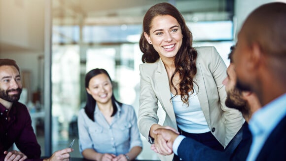 mulher sorridente a cumprimentar homem em sala de reuniões mulher sorridente a cumprimentar homem em sala de reuniões