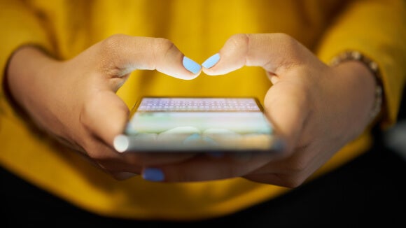 pormenor mãos de mulher com smart phone e camisola amarela