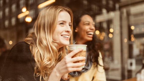 duas mulheres sorridentes com café