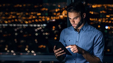 Homem com tablet às escuras